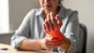 Frau hält schmerzend ihr Handgelenk – Symptom einer Sehnenscheidenentzündung im Handgelenk