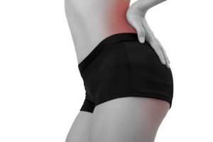 Frau in schwarzen Shorts, die sich von hinten die Hüfte hält. Diese ist in Rot eingefärbt und signalisiert schmerzen.